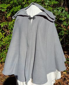 This short cloak is delightfully soft and comfortable. It's long enough to reach the back of the hand, keeping you warm but keeping your hands available when needed. It has a full hood and closes with a matching cloth frog clasp. This cloak is great for a costume piece or a cozy jacket, great for Spring, Fall, or over air conditioned buildings. Your cloak will measure about 30 inches in length. This listing is in a medium grey, but other colors are available in my store or on request. The materi Winter Outdoor Cape, Gray Winter Cape Outerwear, Gray Winter Cape, One Size Outdoor Cape Outerwear, One Size Cape For Outdoor, One Size Outdoor Cape, Solid Hooded Cape For Fall, Hooded Fall Cape For Larp, Hooded Cape For Larp In Fall