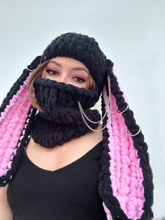 a woman wearing a knitted scarf with pink and black strips on the ends, covering her face