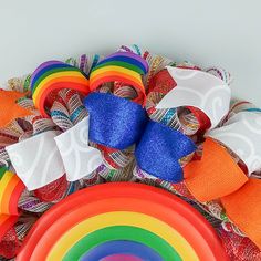 a rainbow colored frisbee sitting on top of a mesh wreath with ribbons around it