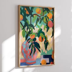 a painting hanging on the wall next to a vase filled with oranges and green leaves