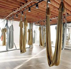 a room filled with lots of hanging curtains and wooden flooring next to large windows