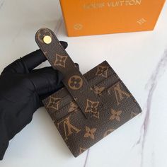 a hand holding an item in front of a louis vuitton box