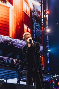 a man standing on top of a stage holding a microphone to his mouth and singing