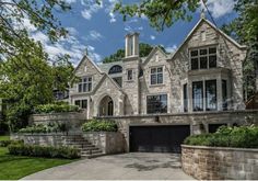 a large stone house with two car garages on the front and side of it