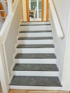 a set of stairs leading up to an open door in a white room with wood trimming