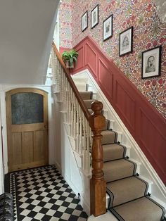 the stairs in this house are decorated with floral wallpaper and framed pictures on the wall