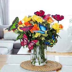 a glass vase filled with colorful flowers on top of a table next to a couch