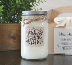 a jar filled with white candles sitting on top of a table next to a box