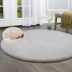 a large round rug in the middle of a living room with a hand on it