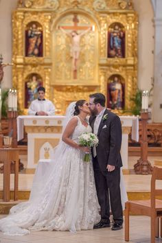 a bride and groom kissing in front of the alter