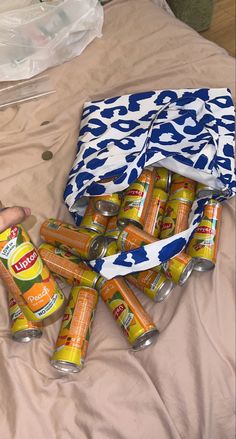 several cans of orange soda on a bed