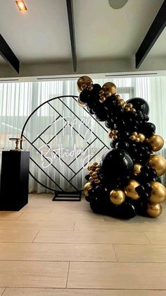 a large black and gold balloon tree in the middle of a room