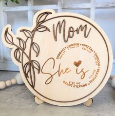 a wooden plaque that says mom she is surrounded by leaves and hearts with the word, she is