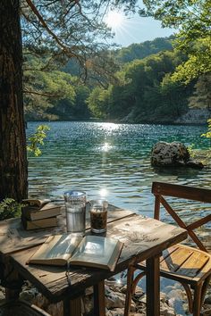 an open book sitting on top of a wooden table next to a lake filled with water