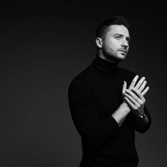 a black and white photo of a man holding his hands together