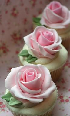 three cupcakes with pink frosting and roses on them