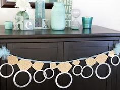 a black dresser topped with a blue vase filled with flowers and paper circles hanging from it's sides