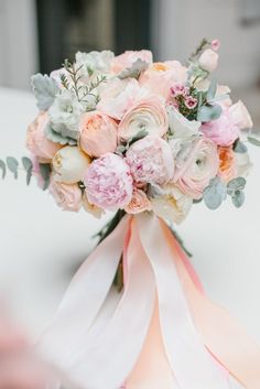 a bridal bouquet with pink flowers and greenery on the table at a wedding