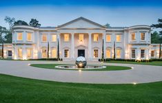 a large white house with lots of windows and lights on it's front lawn