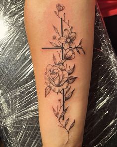 a cross with flowers on the side of her leg and an arrow in the middle