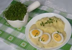 a plate with eggs, mashed potatoes and gravy on it next to a potted plant