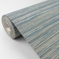 a roll of blue and beige striped wallpaper on a white surface with a grey background