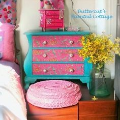 a pink and blue dresser sitting next to a bed