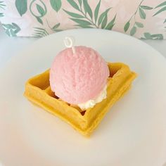 a waffle topped with ice cream on top of a white plate next to a green leafy pillow