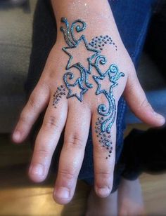 a child's hand with blue and white designs on the palm, which is decorated with stars