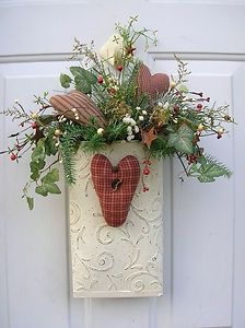 a white door with a red heart hanging from it's side and flowers in the front