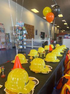 yellow hard hats are lined up on a table at a children's birthday party