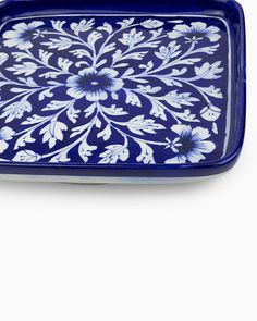 a blue and white tray with flowers on the bottom, sitting against a white background