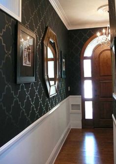 the hallway is decorated with black and white wallpaper, wood flooring and framed pictures