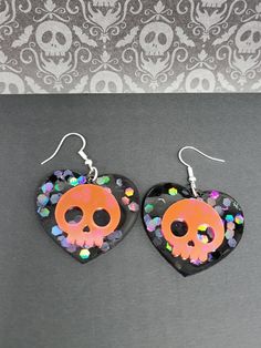 Holographic and Black Light Reactive, black and pink, heart skull Resin earrings. These are holographic and that shows best in bright light or sunshine. They were made with Black light reactive powder which shows best in that lighting. The black heart back of these also has holographic glitter flecks in it. . They are total length from top of hook to bottom is  2.25" inches they are 1.5  Inches wide. The earring hooks are Stainless Steel.  Do you like this style earring but would like it in a di Black Skull Print Earrings As Gift, Novelty Black Skull Earrings, Black Glow In The Dark Jewelry For Parties, Black Glow In The Dark Party Jewelry, Black And Pink Heart, Holographic Black, Heart Skull, Utica Ny, Skull Earrings