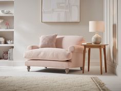 a living room with a pink chair, table and bookshelf in the background