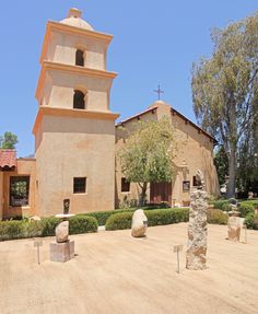 an old church in the middle of a dirt lot with trees and bushes around it