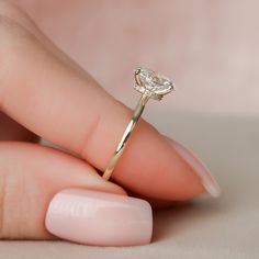 a woman's hand holding a diamond ring on top of her finger, with the middle