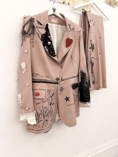 two jackets hanging up on a wall with clothes pins attached to the jacket and tie