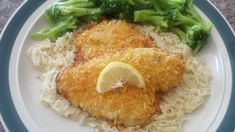 two pieces of chicken on top of rice with broccoli and lemon wedges