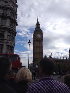 the big ben clock tower towering over the city of london as people watch from across the street