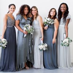 a group of women standing next to each other wearing dresses and holding bouquets in their hands