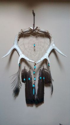 a dream catcher with antlers and feathers hanging on the wall