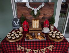 a table topped with cakes and cupcakes covered in frosting next to a deer head