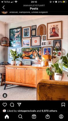 a room with many pictures on the wall and plants in vases next to it