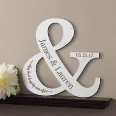 a couple's initials and date sit on top of a shelf next to a flower