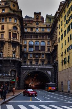 cars are driving under an overpass in a city with tall buildings on either side