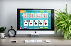 a computer screen with playing cards on it next to a clock and potted plant