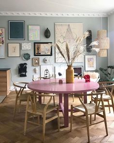 a dining room table with chairs and pictures on the wall