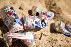 three cans of pepsi are laying on the ground next to each other in the sand