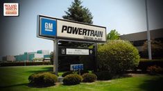 a powertrain sign in front of a building with trees and bushes around it on a sunny day